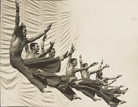 black and white photo of a line of synchronously leaping dancers